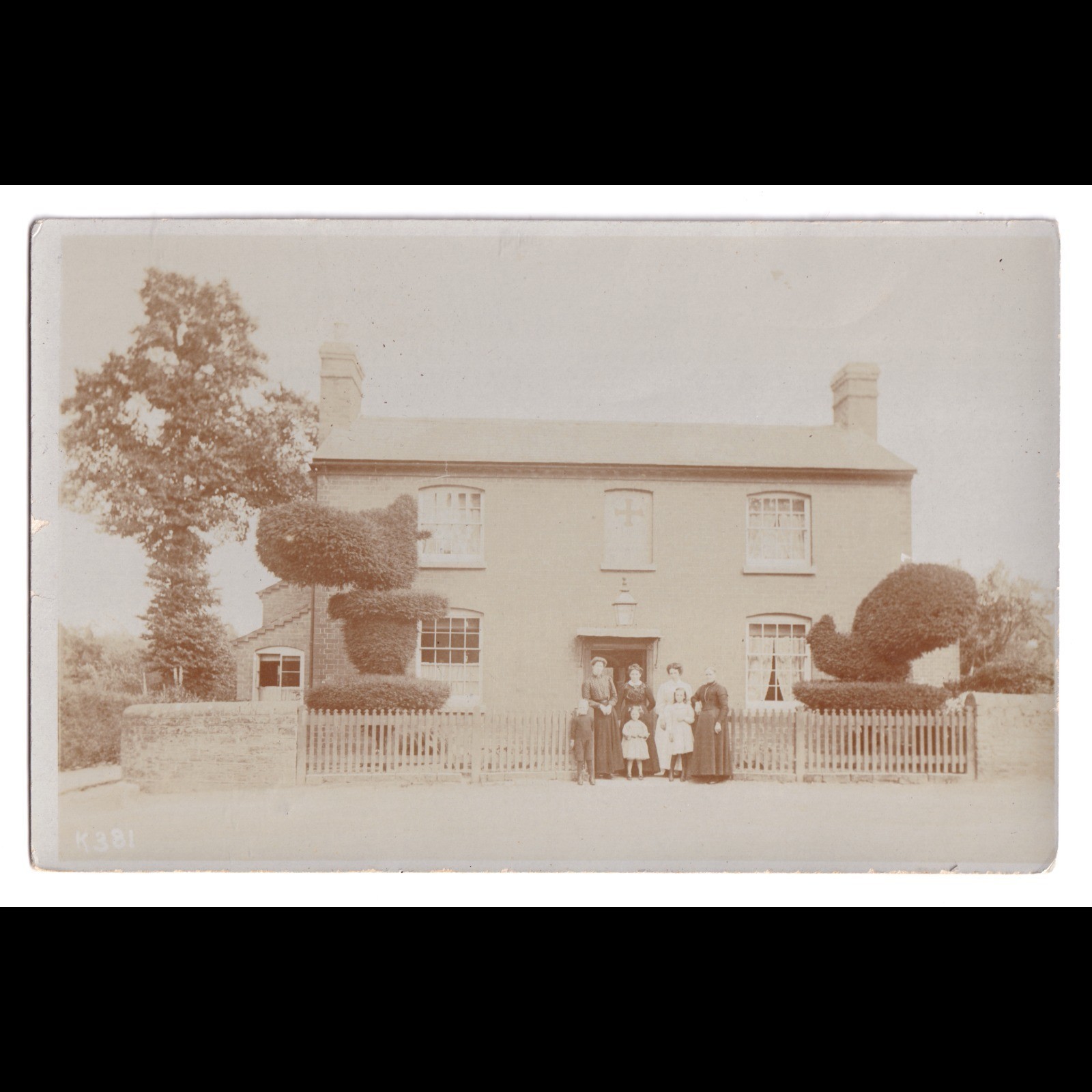 Postcard: Postcard Unidentified House, Family. Distinctive Topiary Bushes, Cross in Window: catalogue image 1
